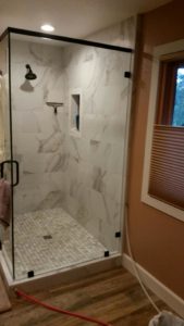 Glass-walled shower in corner of bathroom