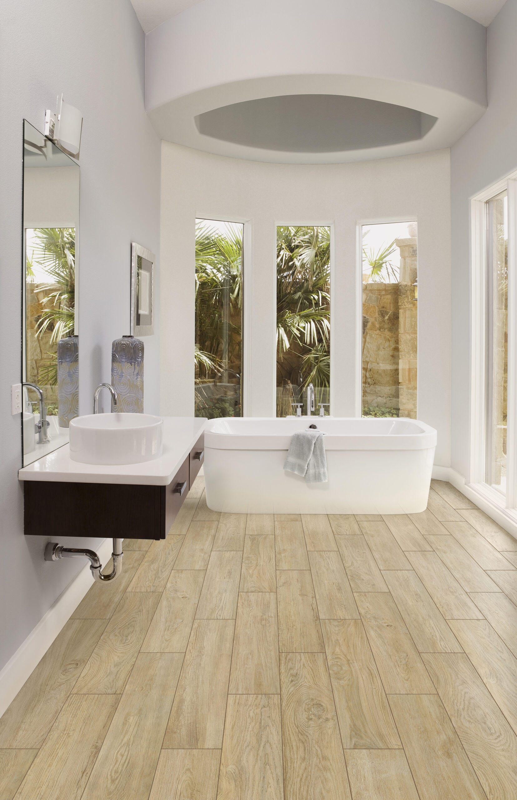 airy bathroom with white walls and tub, light wood look tile floor