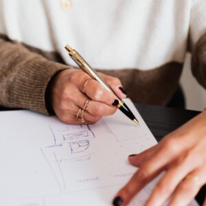 Person sketching floor plan or room layout; only middle of torso and hands are visible