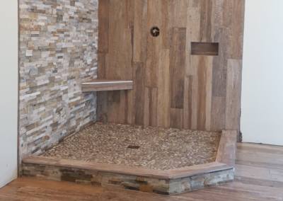 Shower with wood-look tile, quartzite ledger, and pebbles