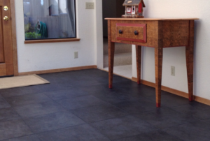 Home entryway with dark tile floor, white walls, and a wooden entryway table