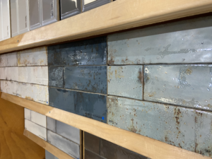 Tiles on a display shelf; featured are several colors of weathered subway tile