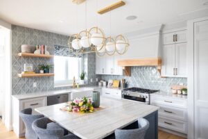 Kitchen featuring pale blue/green diamond backsplash, stone island, white cabinetry, white and gold light fixture