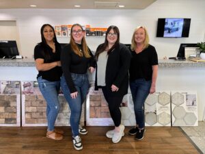 Four women standing together in front of a counter, smiling at the camera