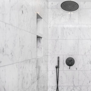 corner of a shower tiled in white and gray marble