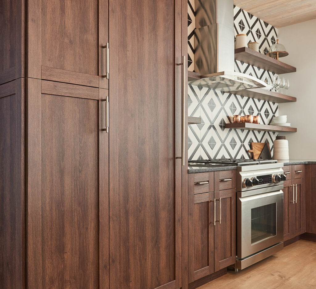 Photo of dark wood cabinetry with black and white graphic tile backsplash over stainless steel range